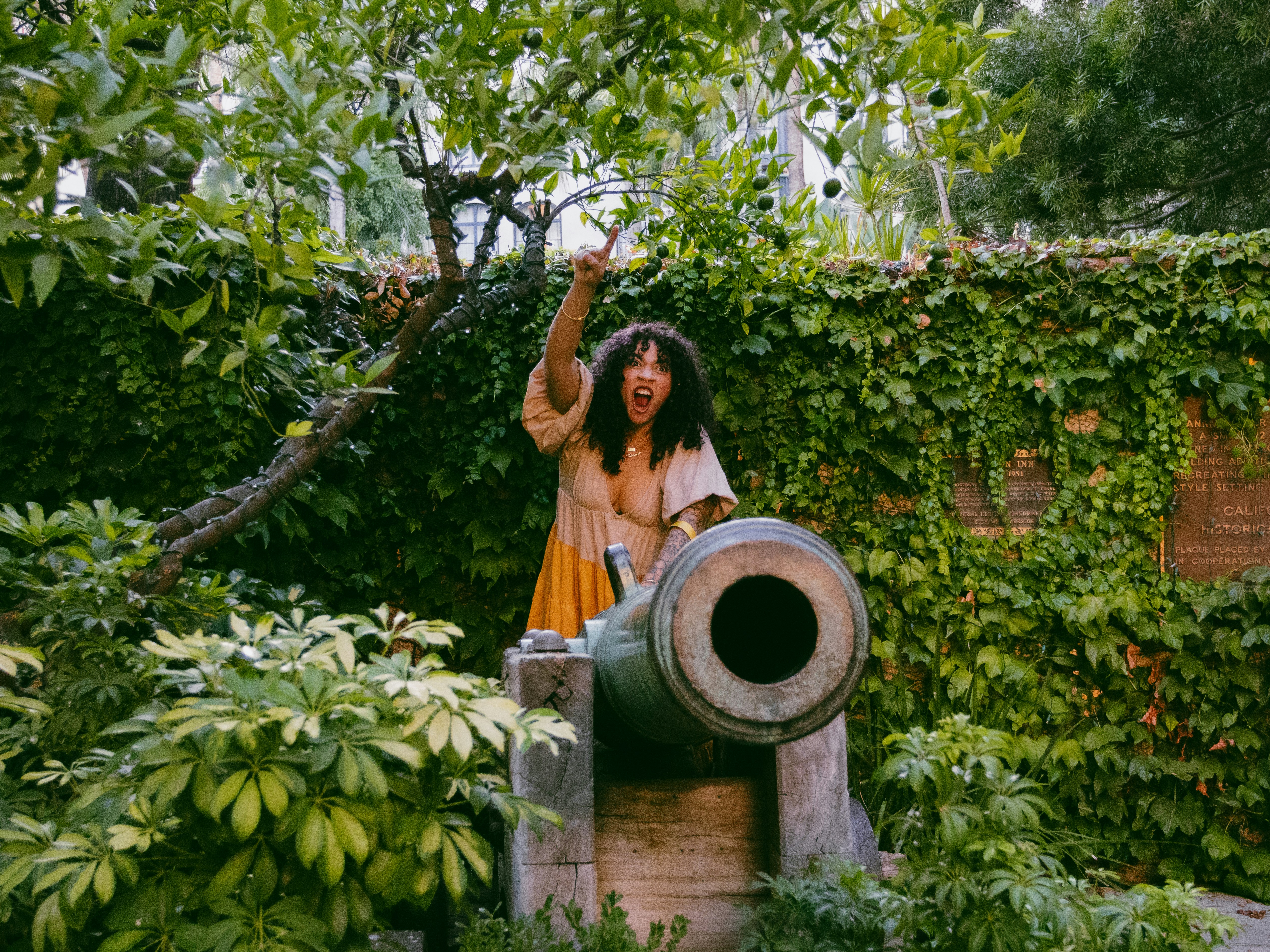 une femme en robe jaune debout dans un jardin