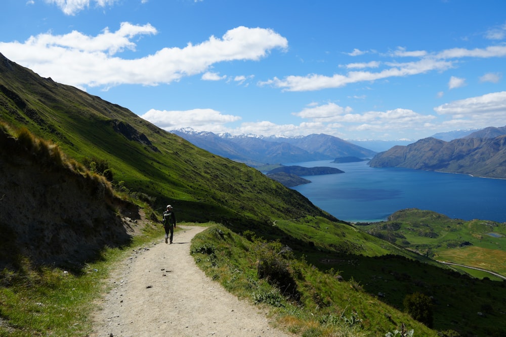 a person walking down a dirt road on a mountain