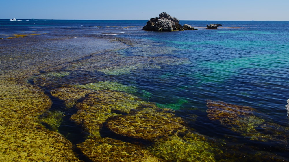 a body of water with rocks in the background