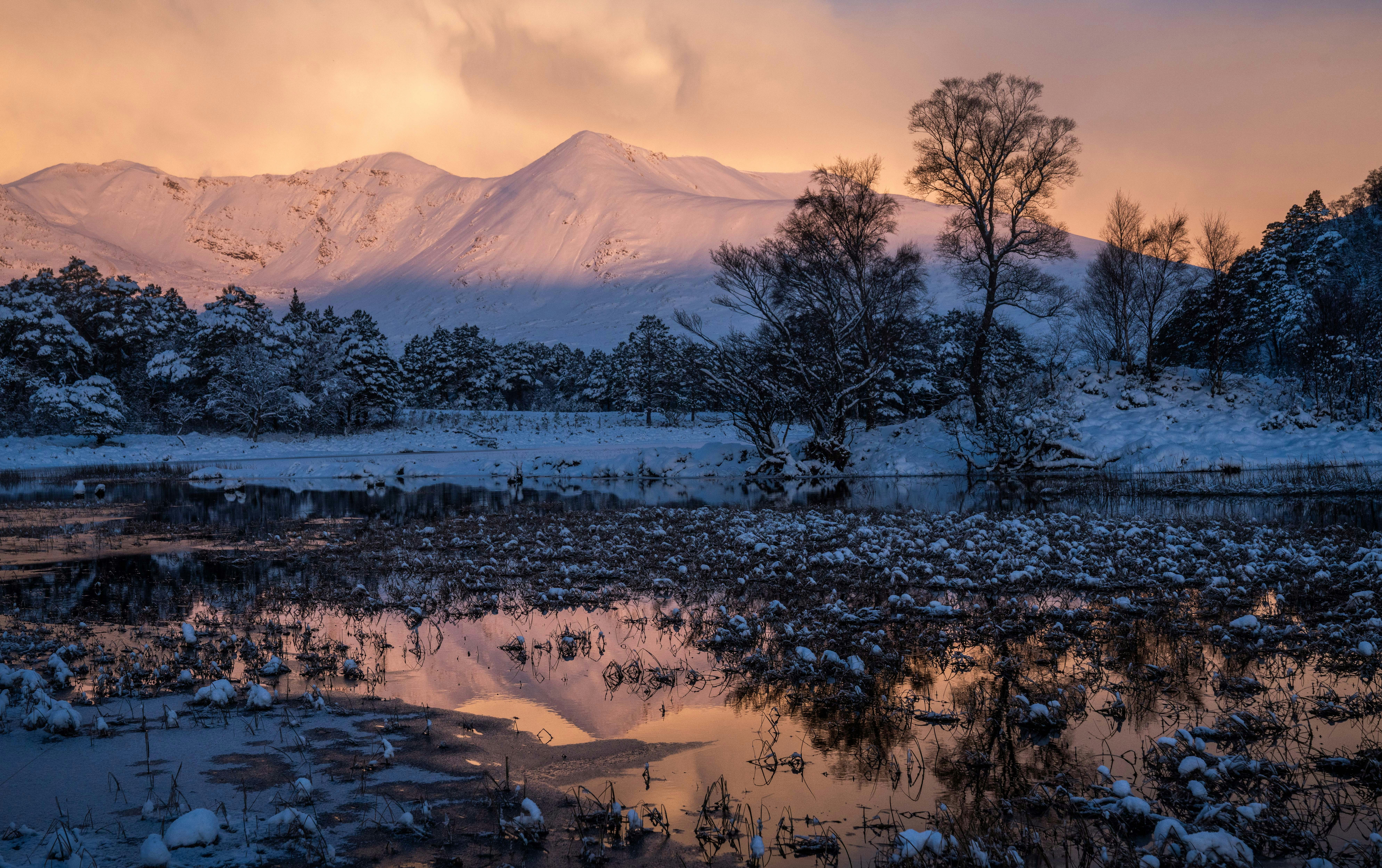 a snow covered mountain range with a lake in the foreground