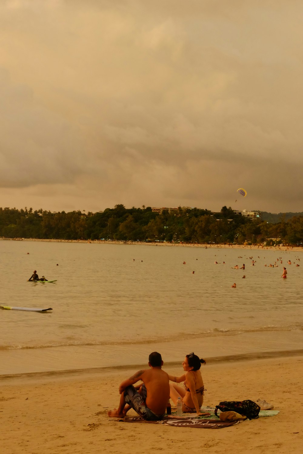 a couple of people sitting on top of a sandy beach