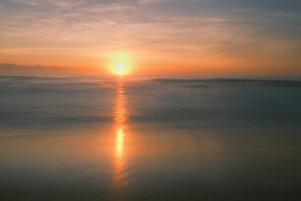 the sun is setting over the water at the beach