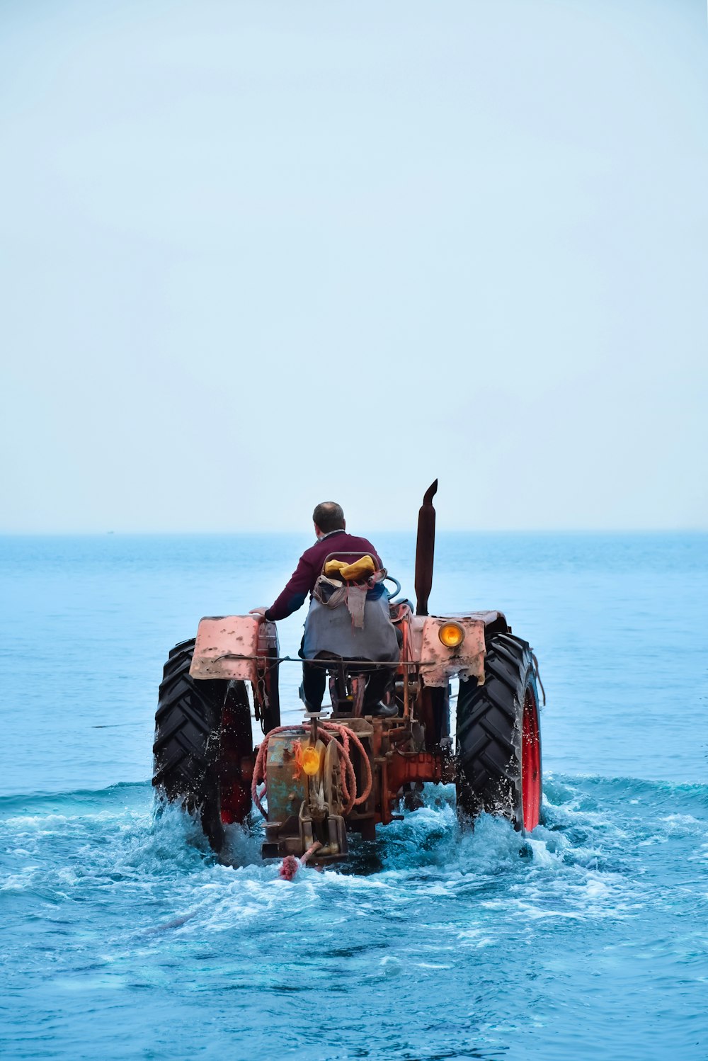 Ein Mann fährt auf der Ladefläche eines Traktors im Meer
