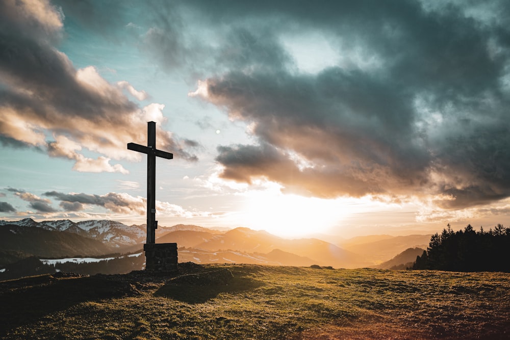a cross sitting on top of a lush green hillside