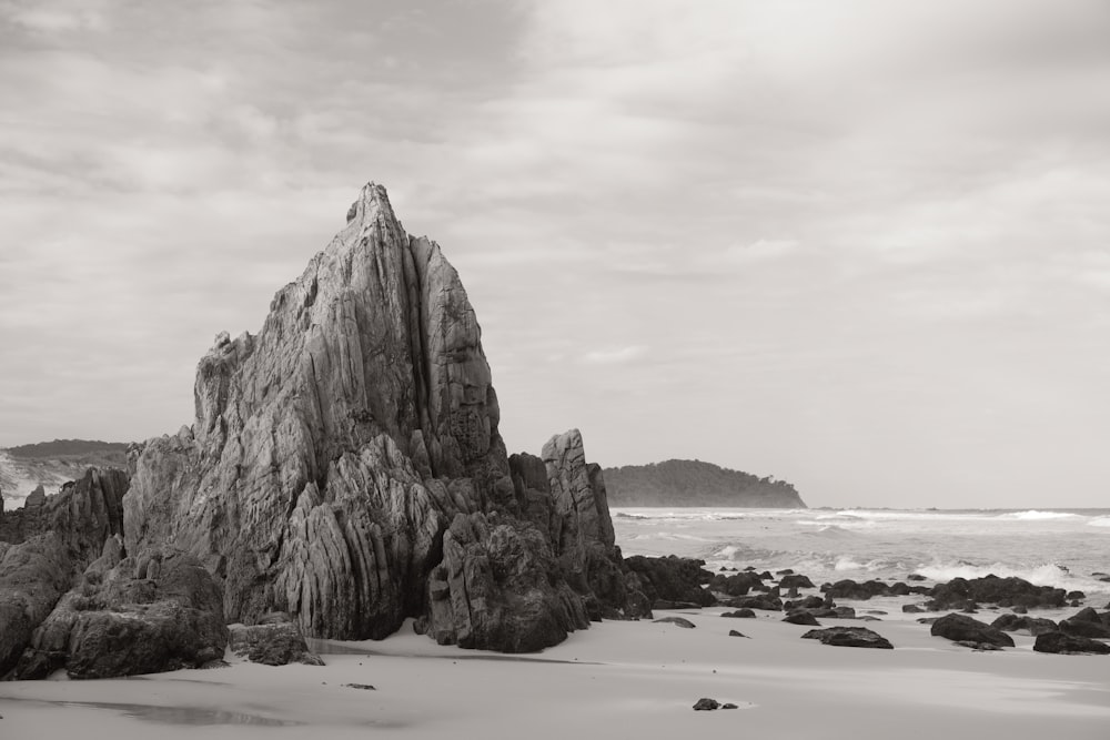 a black and white photo of a rock formation on a beach