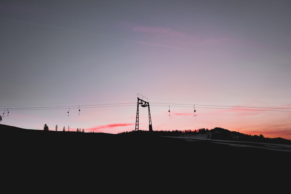 the sun is setting over a hill with power lines