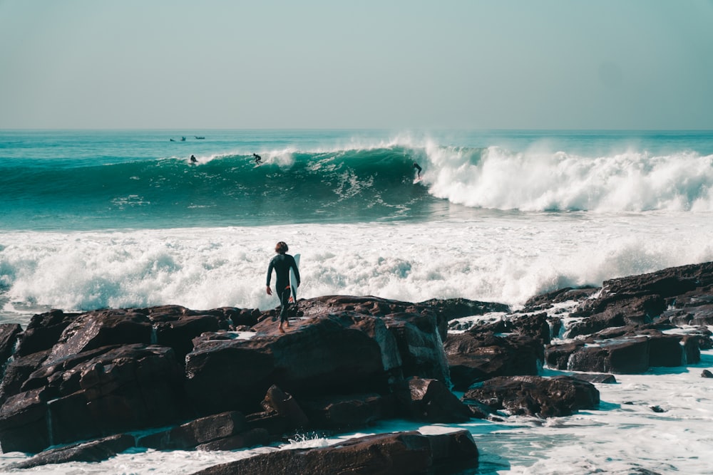 a man standing on rocks looking out at the ocean