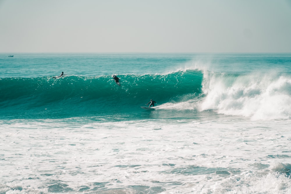 a group of people riding waves on top of surfboards