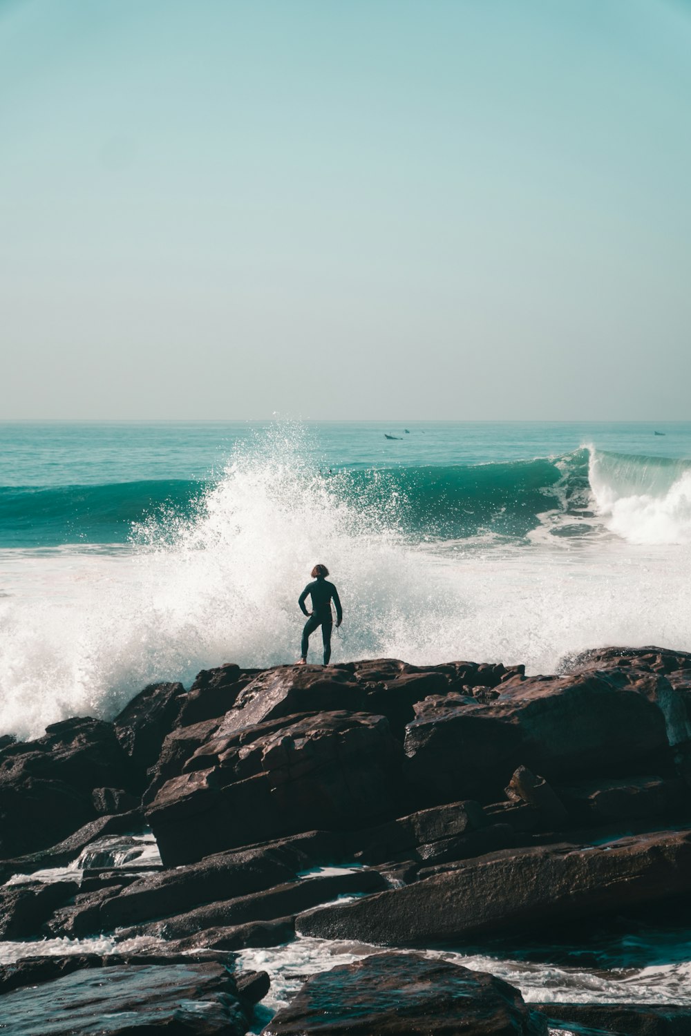 a person standing on a rock near the ocean