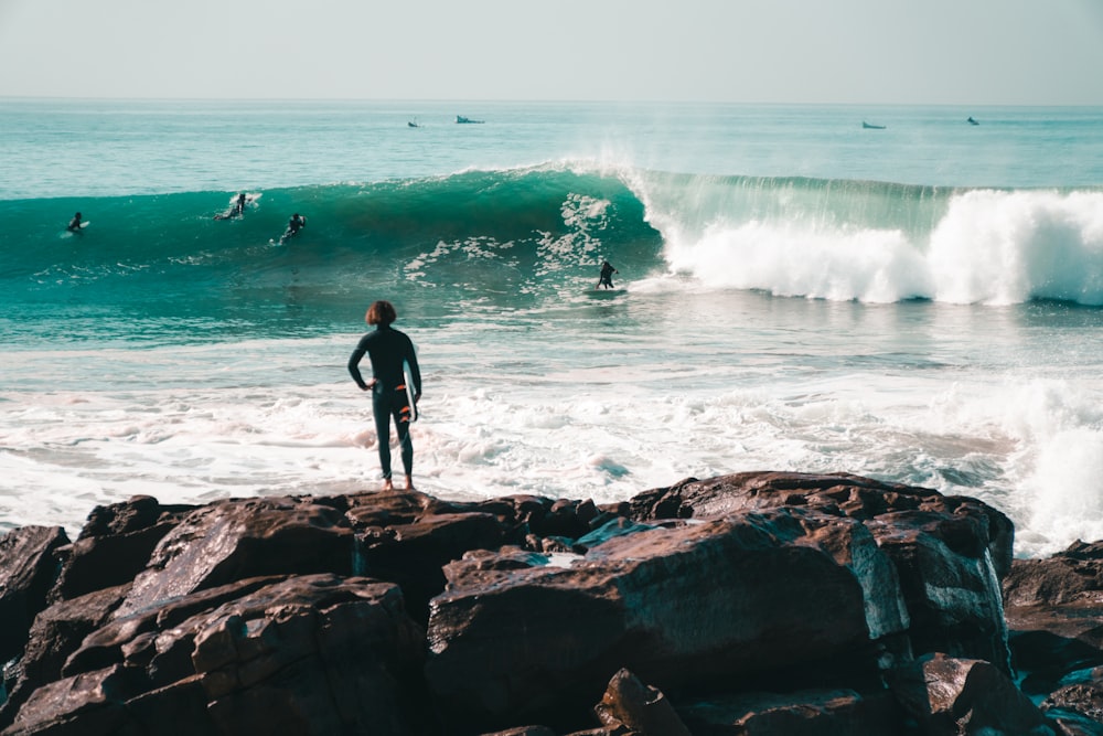 a man standing on a rocky beach next to the ocean