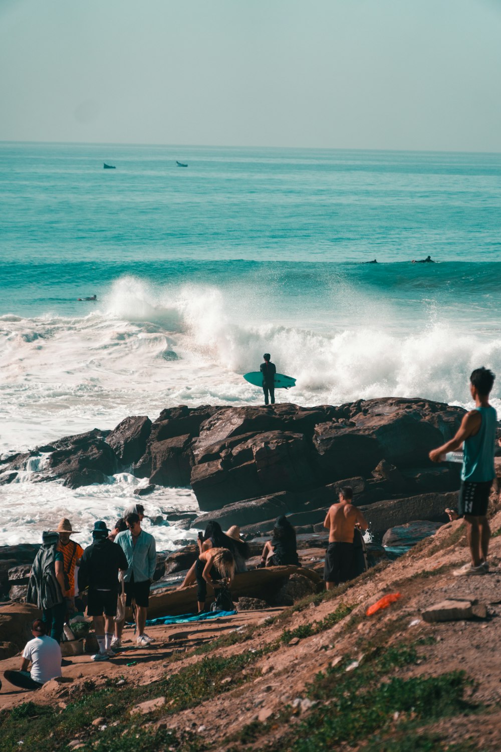 a group of people standing on top of a beach next to the ocean