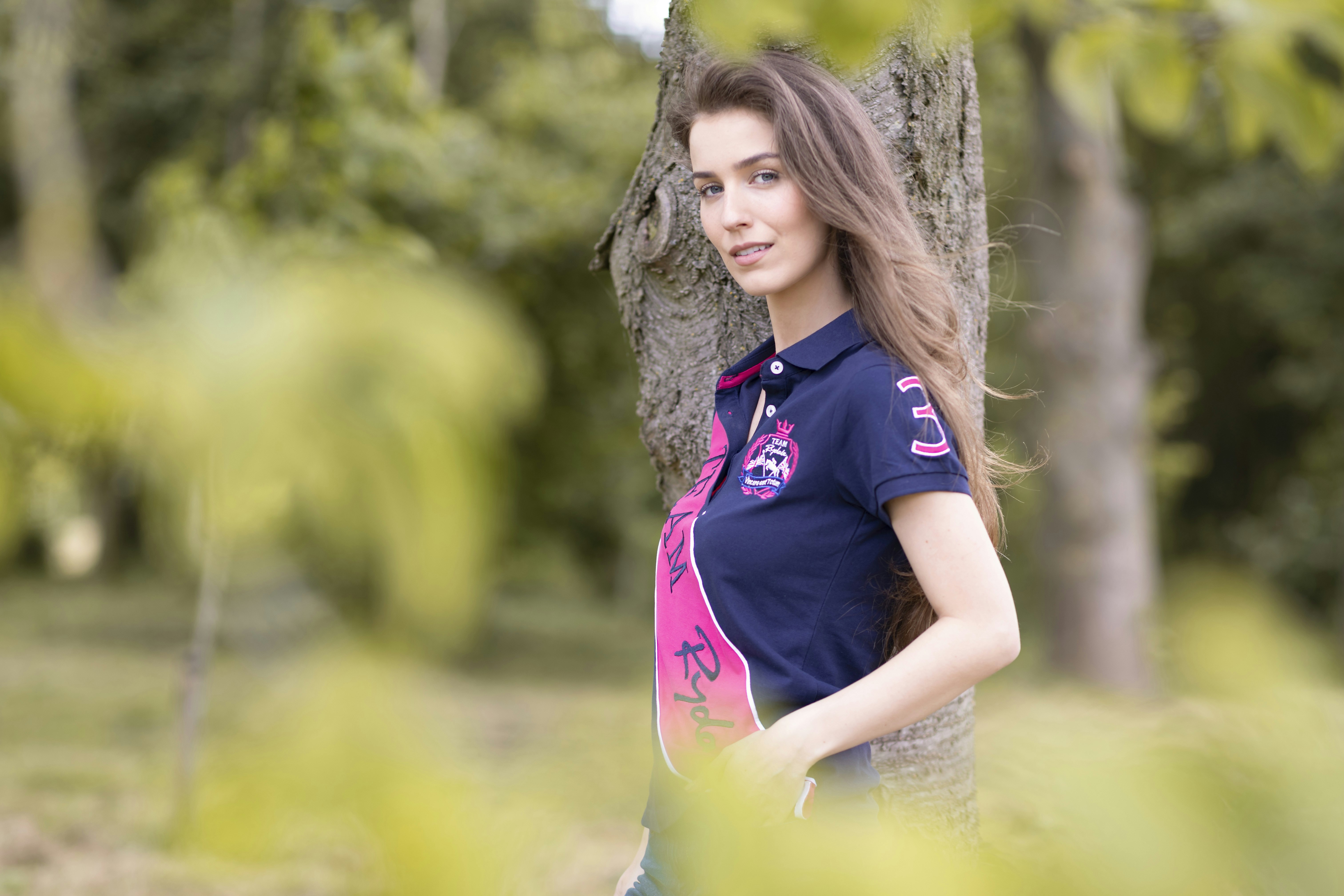 a woman standing next to a tree in a forest