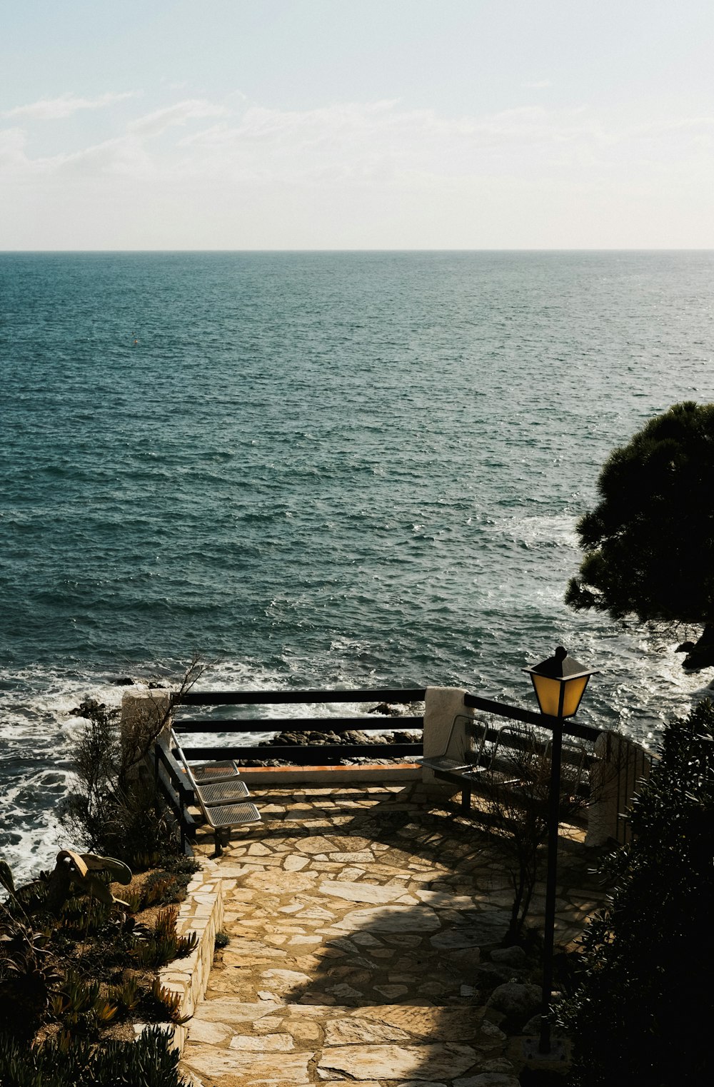 a stone path leading to the ocean on a sunny day