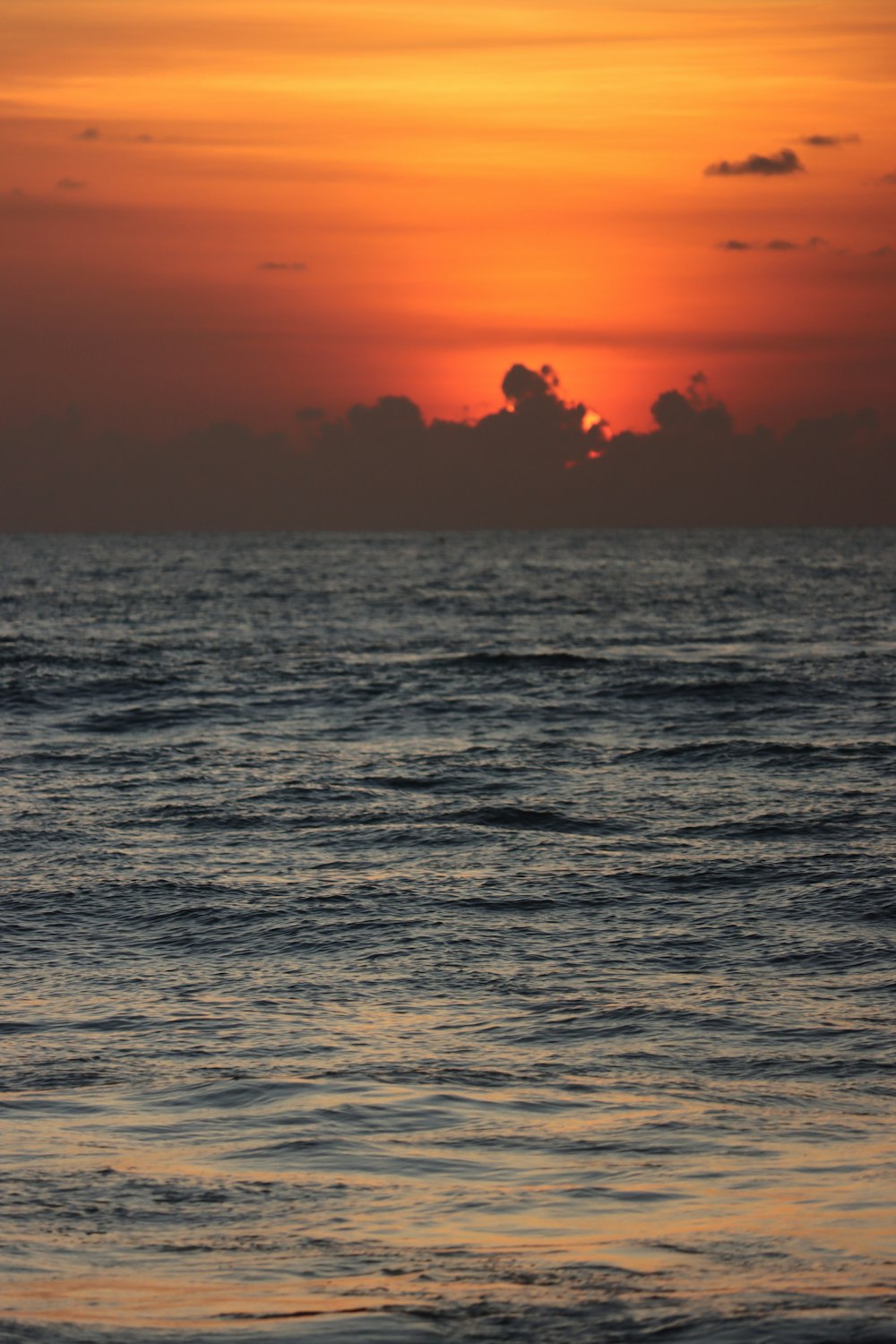 the sun is setting over the ocean with a boat in the water