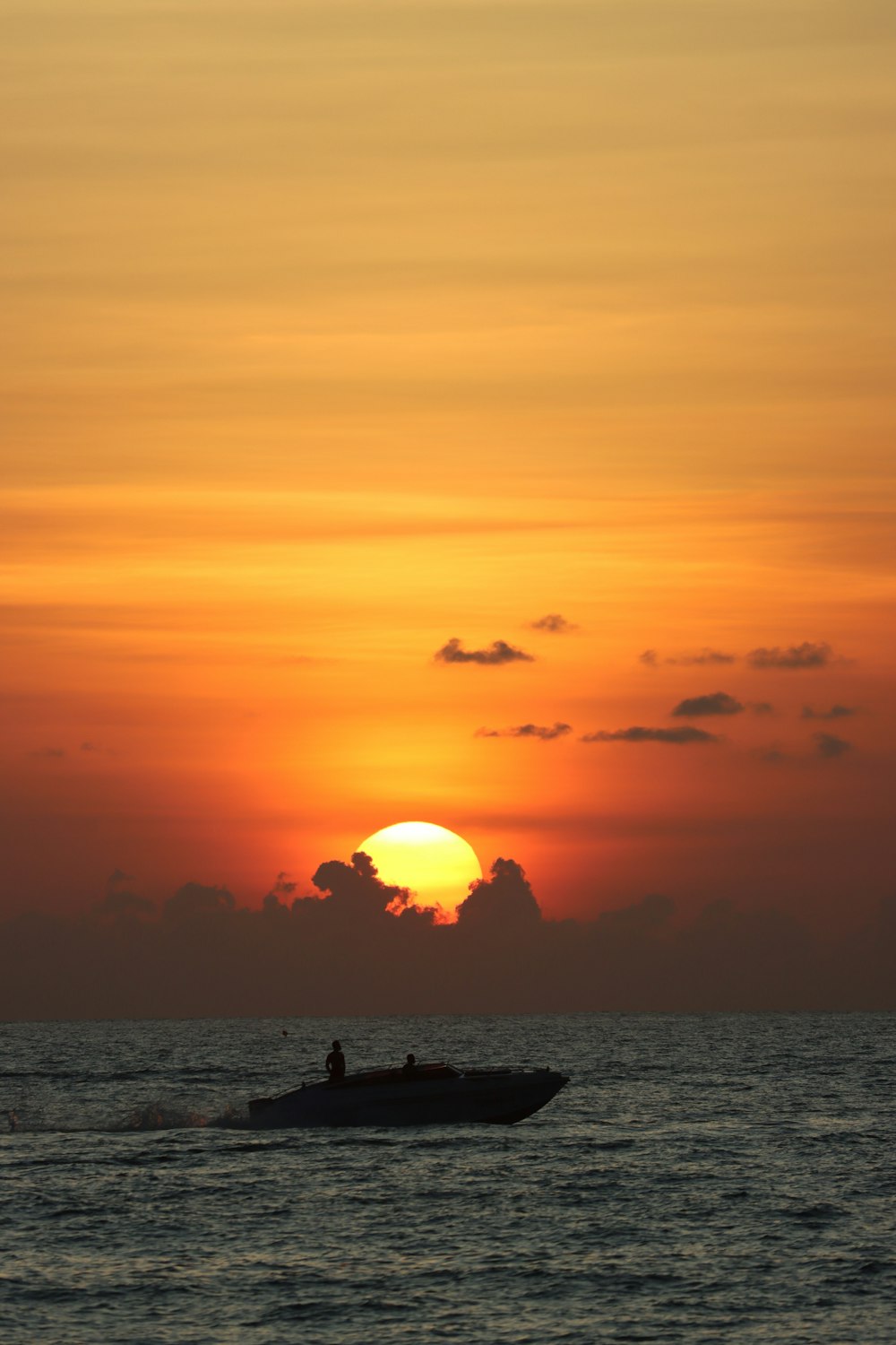 a boat in the ocean with the sun setting in the background