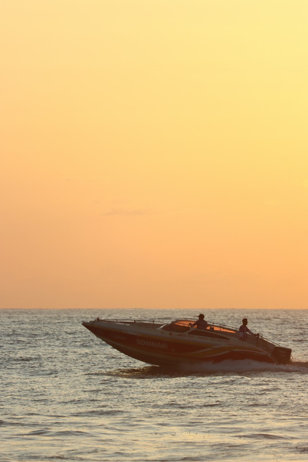 a speedboat is speeding across the water at sunset