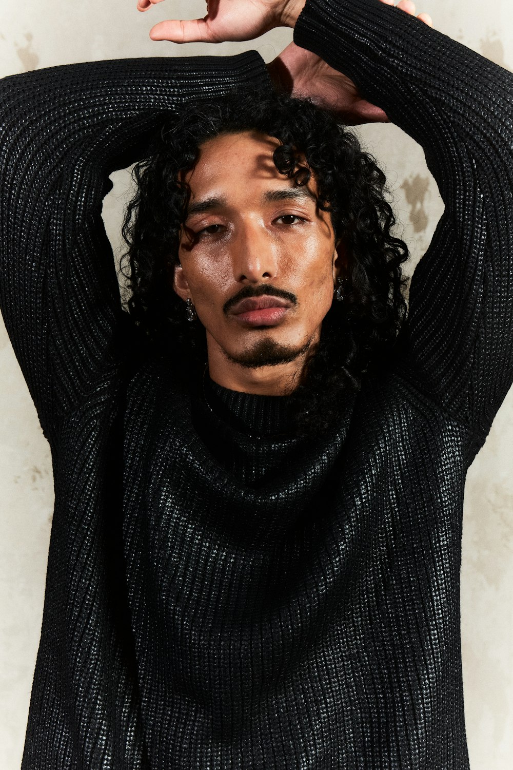 a man with curly hair and a black sweater