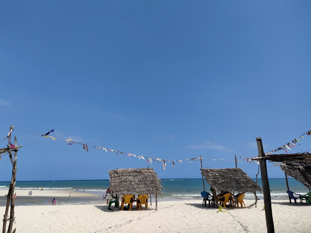 a sandy beach with chairs and thatched huts