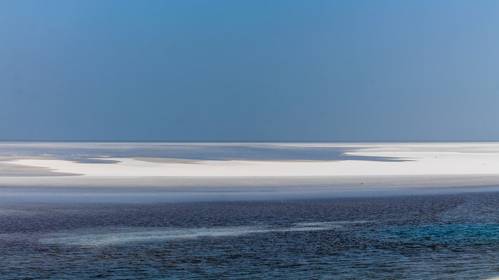 a large body of water sitting under a blue sky