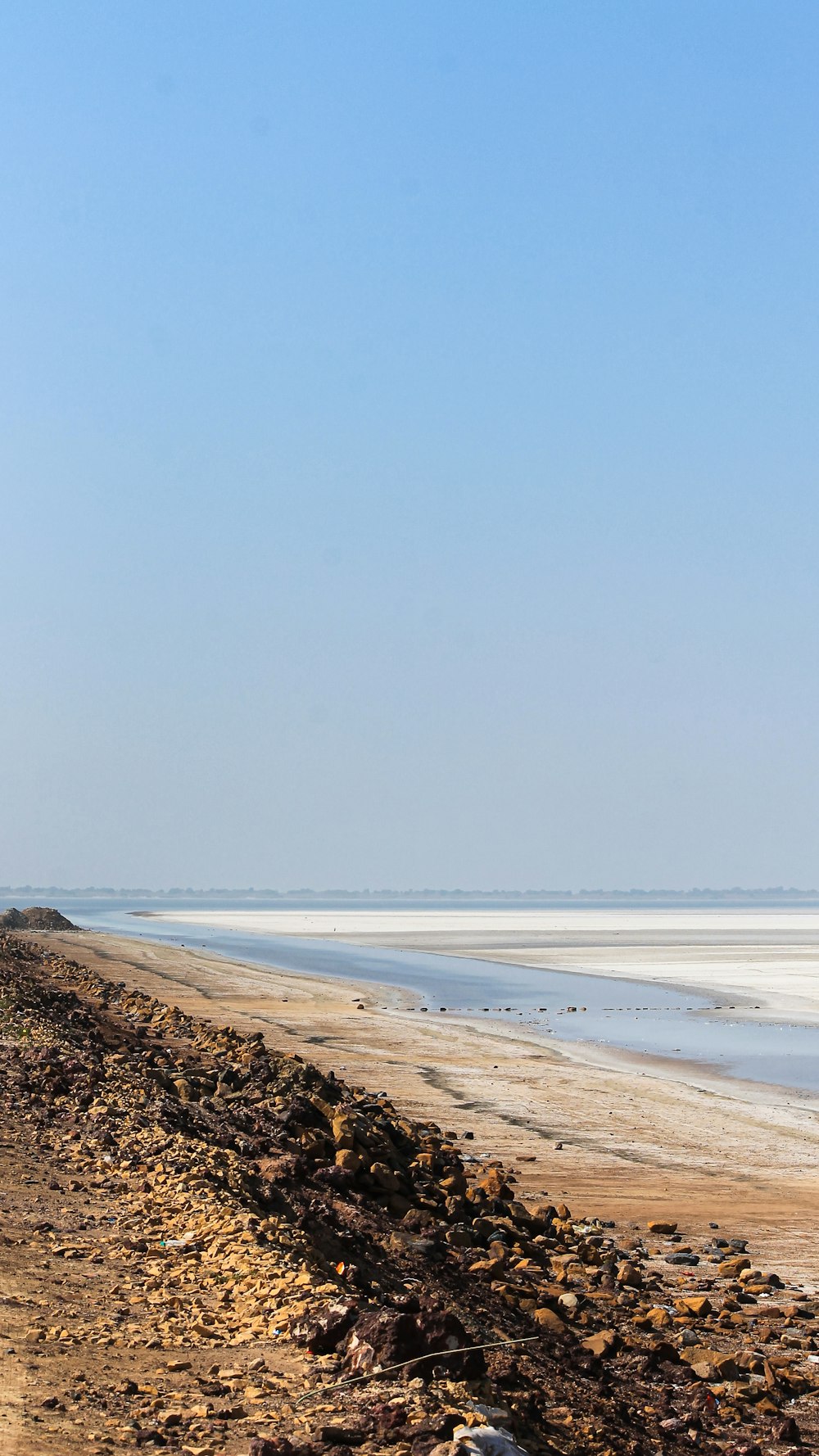 a man riding a horse down a dirt road next to the ocean