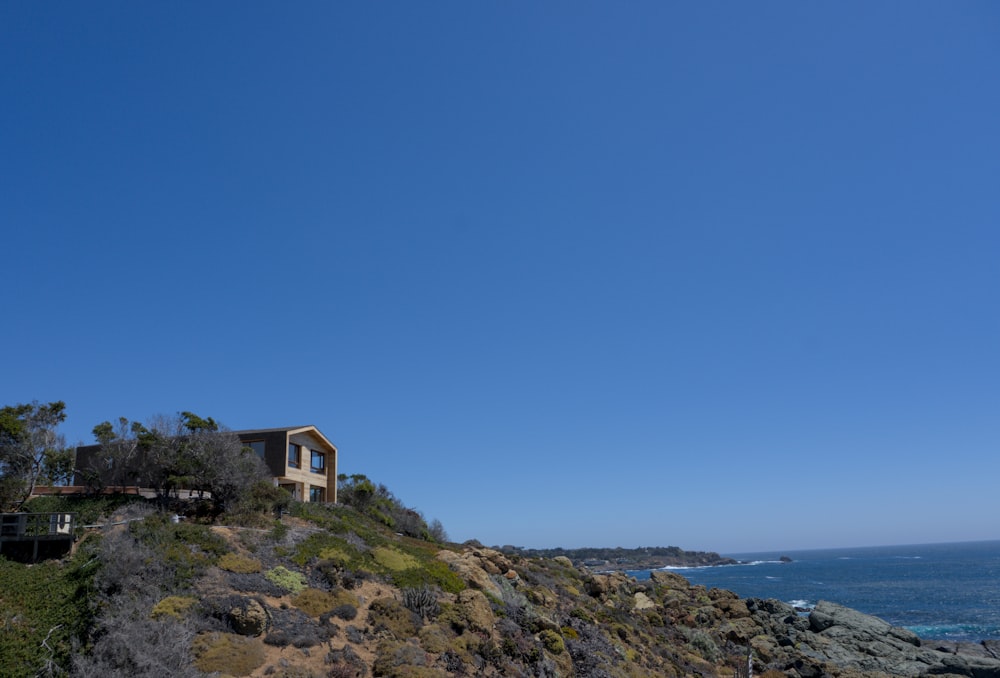a house sitting on top of a hill next to the ocean