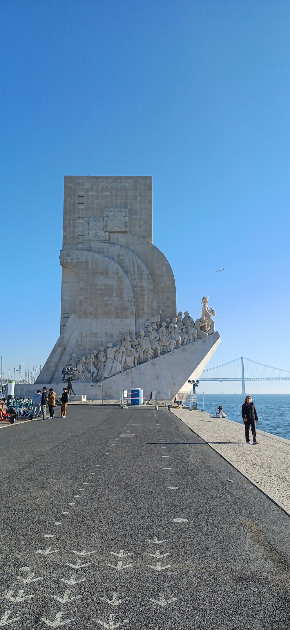 a person walking on a sidewalk near a large monument