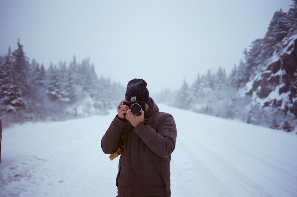 a man taking a picture of a snow covered road