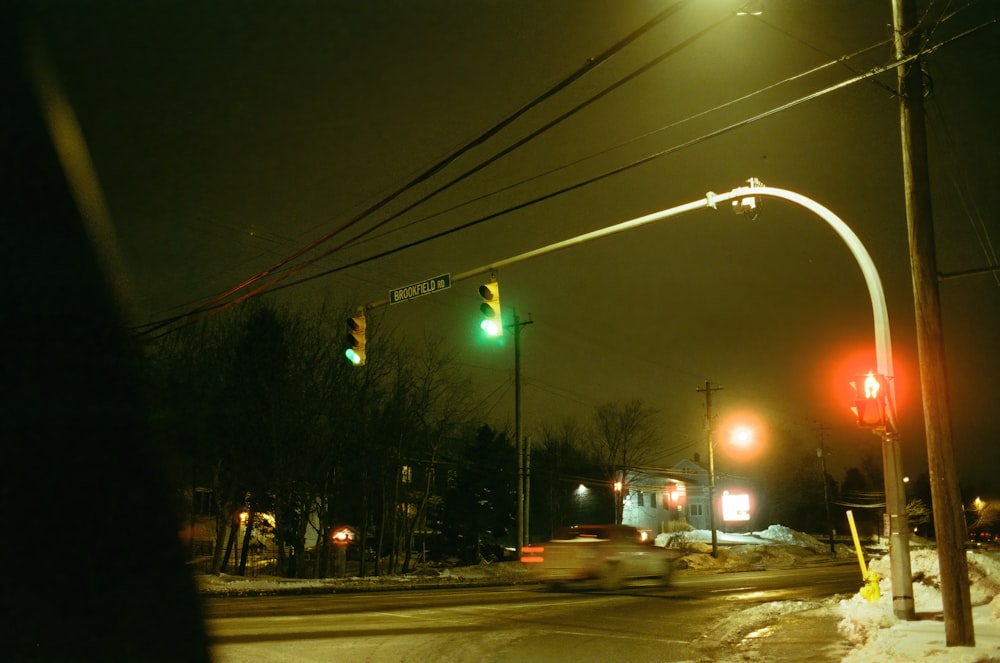 a traffic light on a snowy street at night