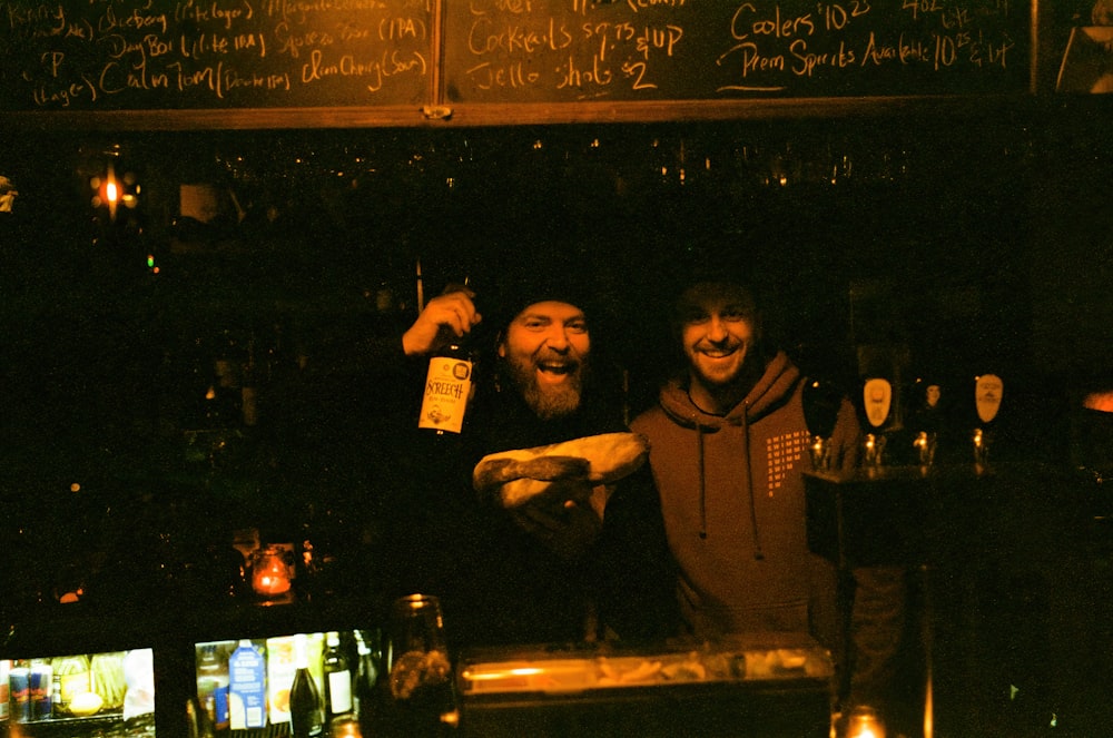 a couple of men standing next to each other at a bar