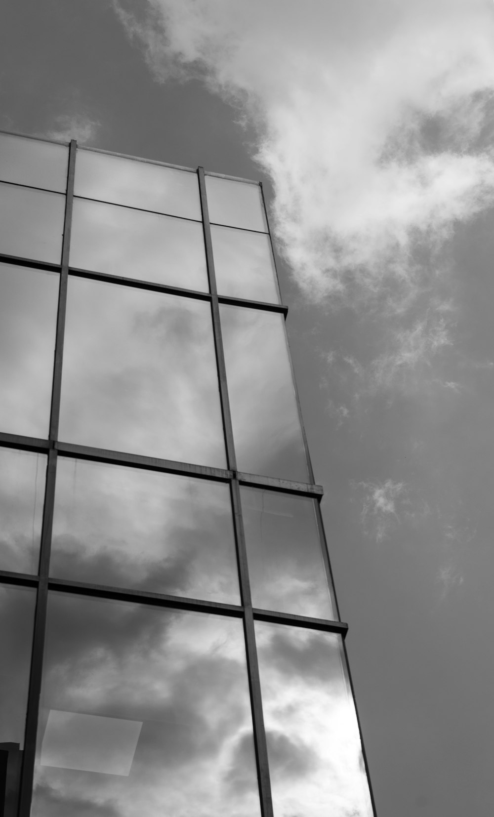 a tall glass building with a cloudy sky in the background
