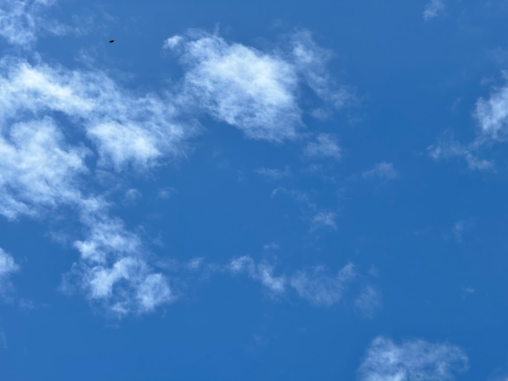 um avião voando através de um céu azul com nuvens brancas