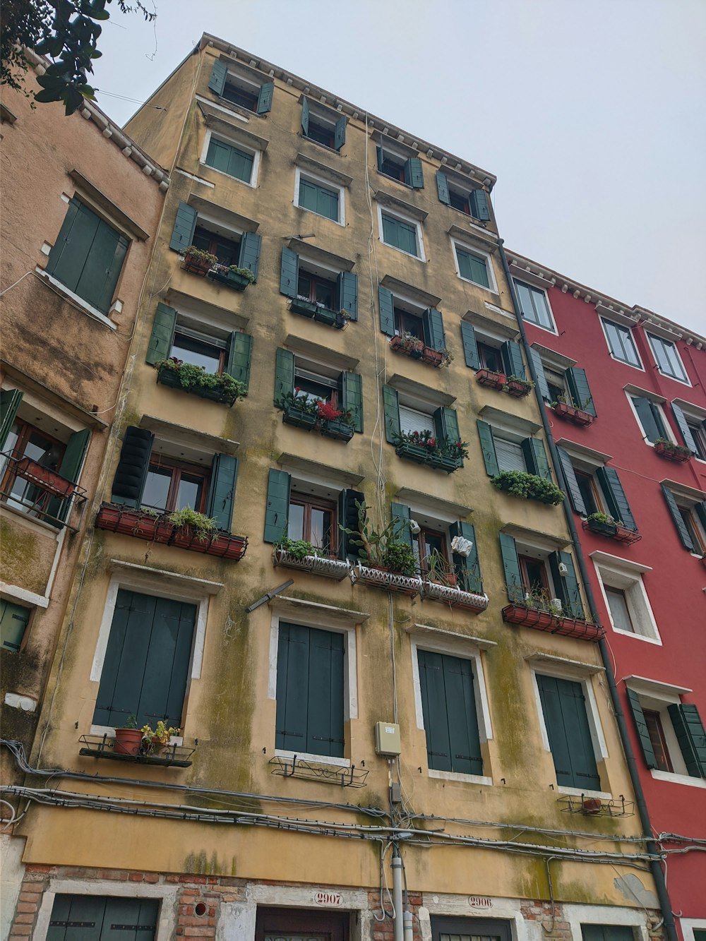 a tall building with many windows and plants on the balconies