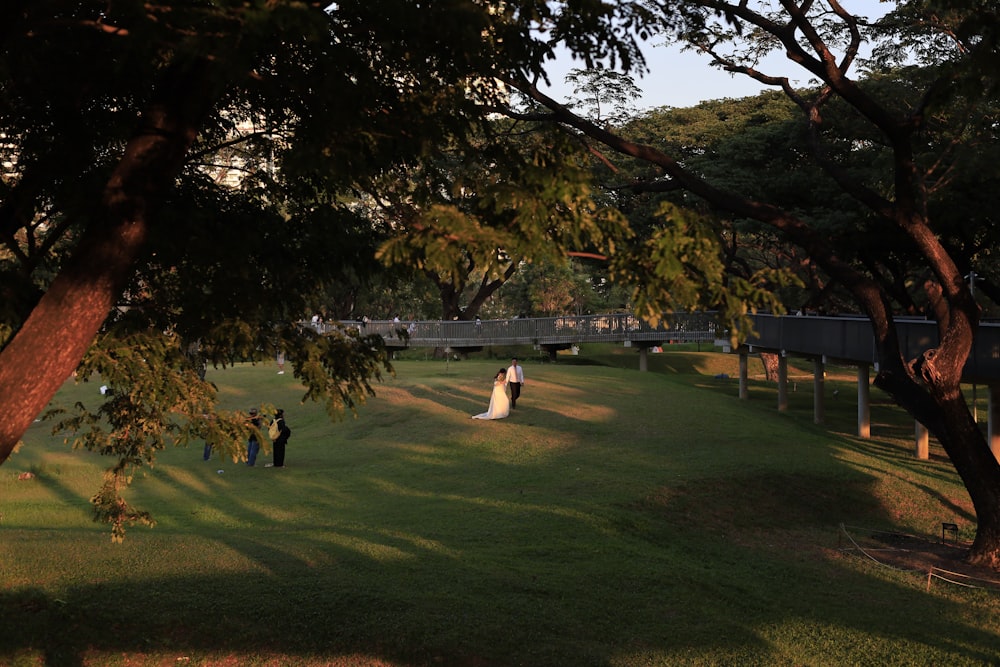 a bride and groom walking through a park