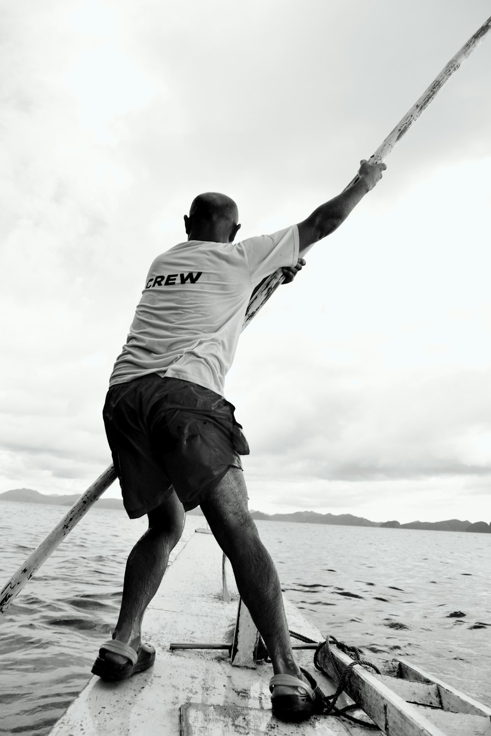 a man on a boat holding onto a pole