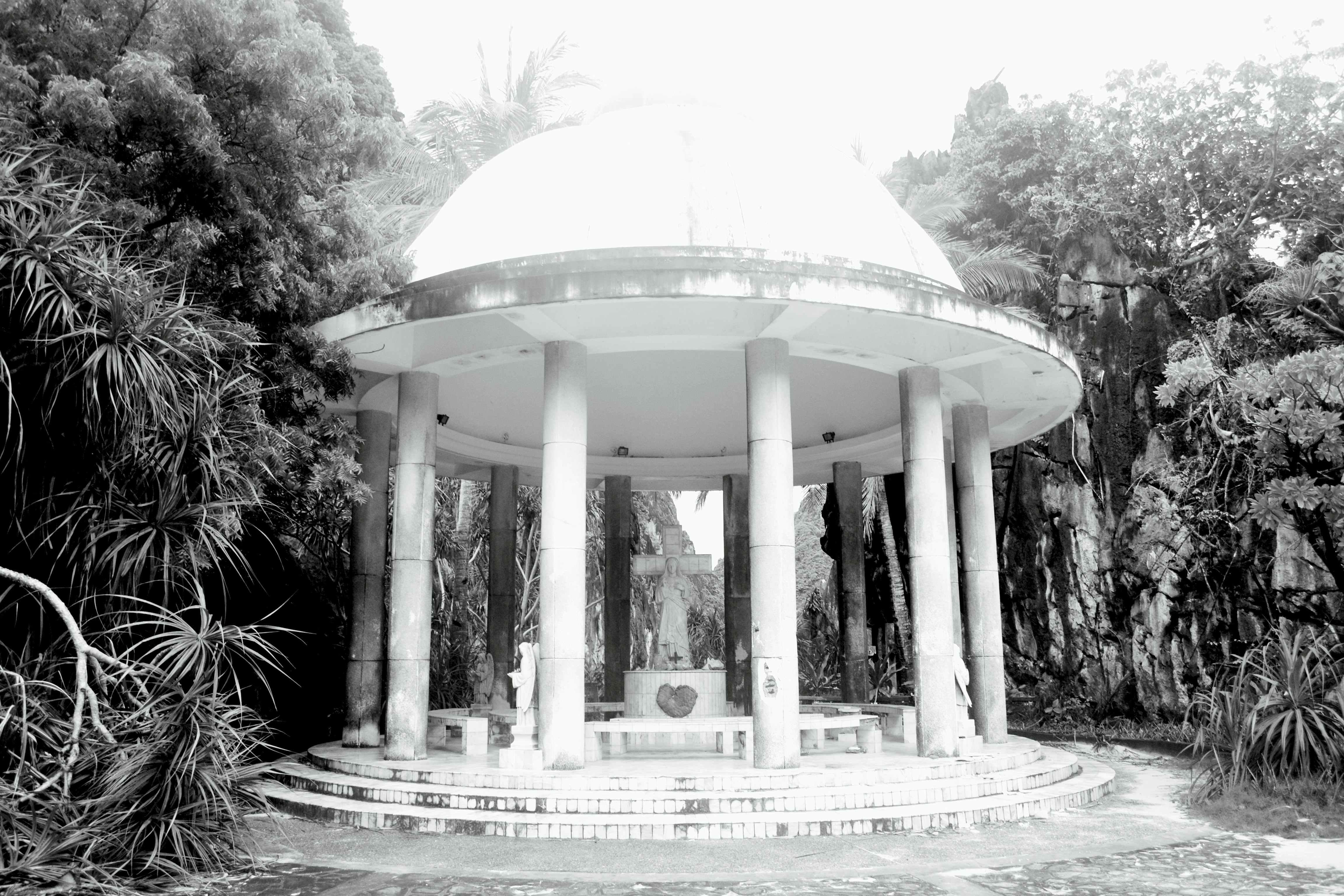 a white gazebo surrounded by trees and bushes