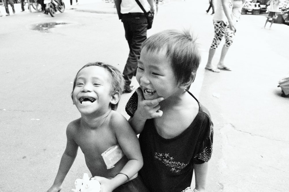 two young boys sitting on the side of a road