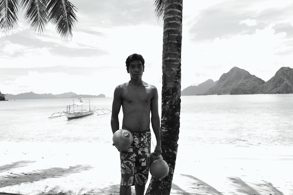 a man standing next to a palm tree on a beach