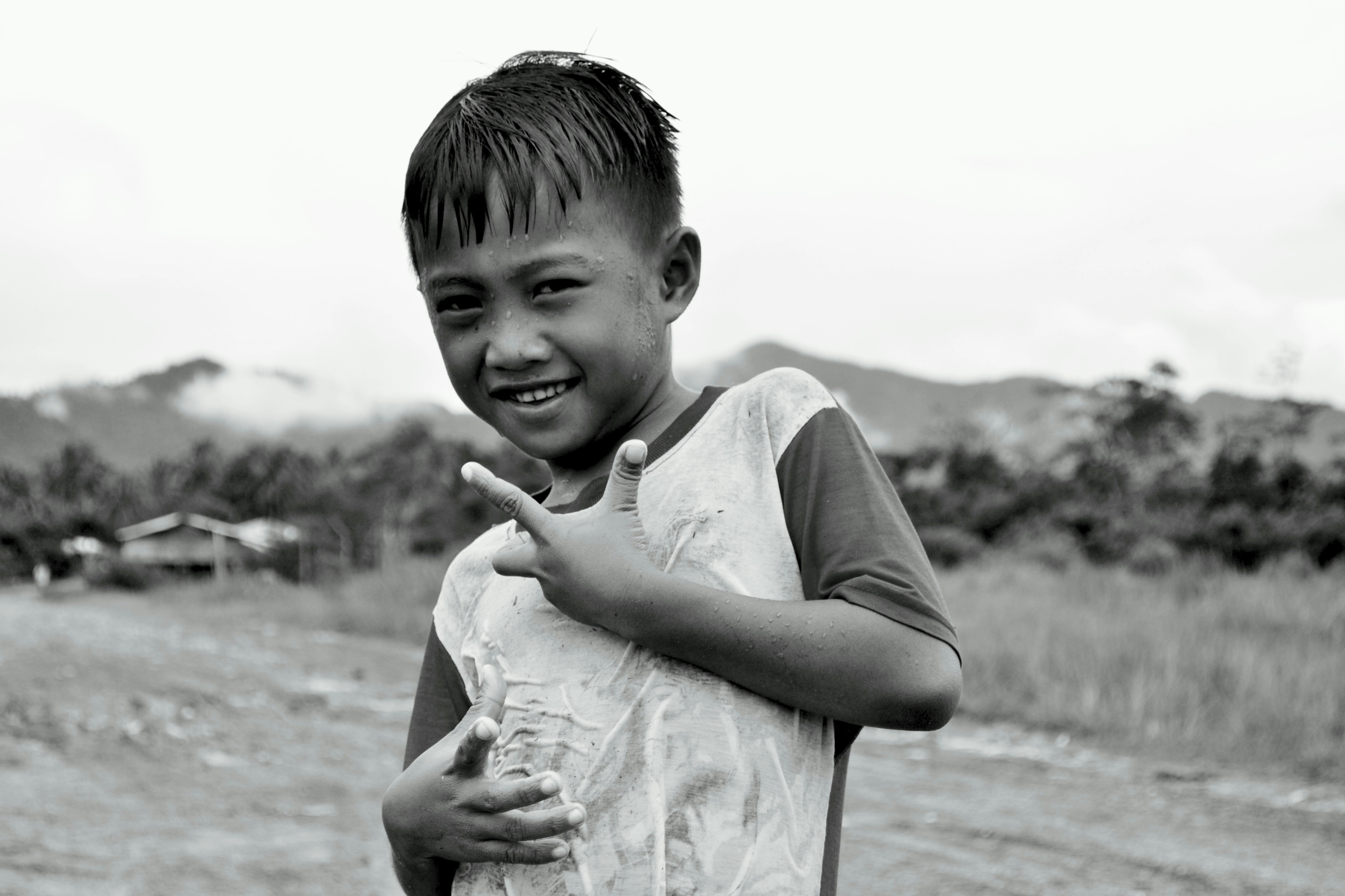 a young boy making a peace sign with his hands