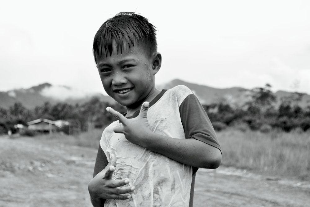 a young boy making a peace sign with his hands