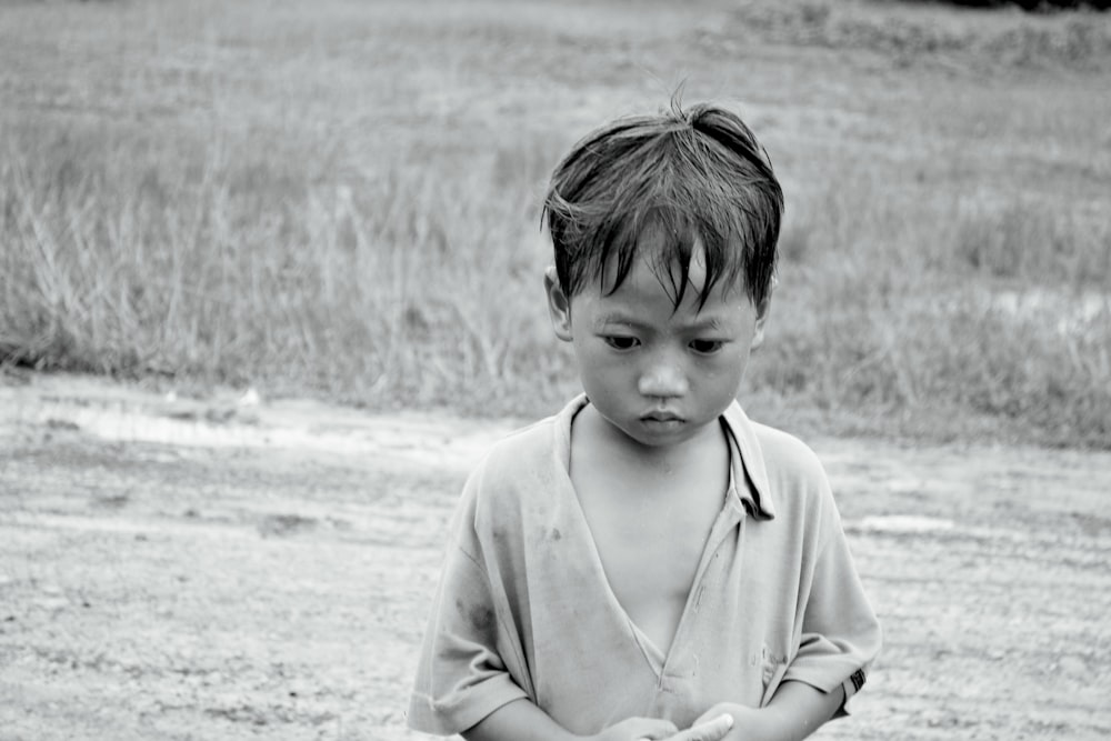 a young boy standing in a field holding a frisbee