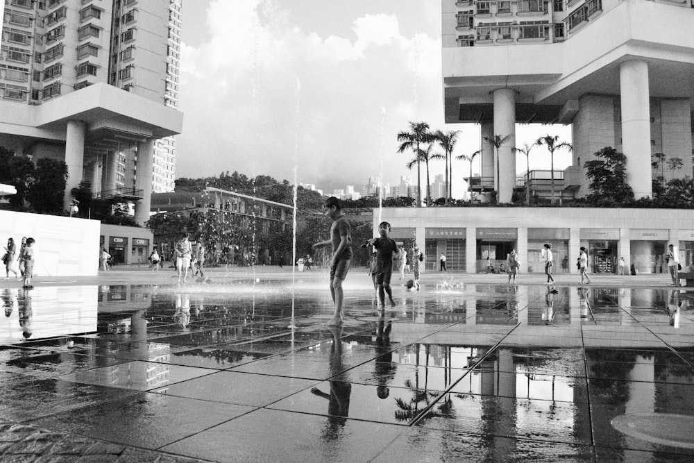 a black and white photo of people playing in a fountain
