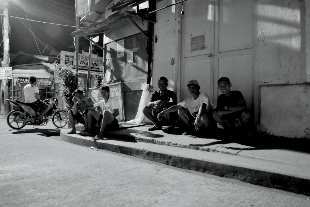 a group of men sitting on the side of a street