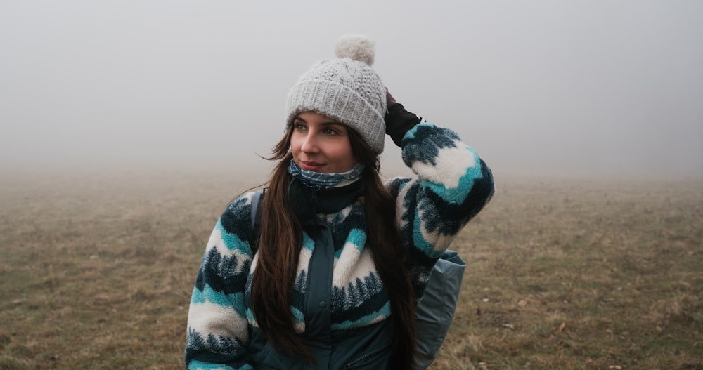 a woman wearing a hat and scarf in a foggy field