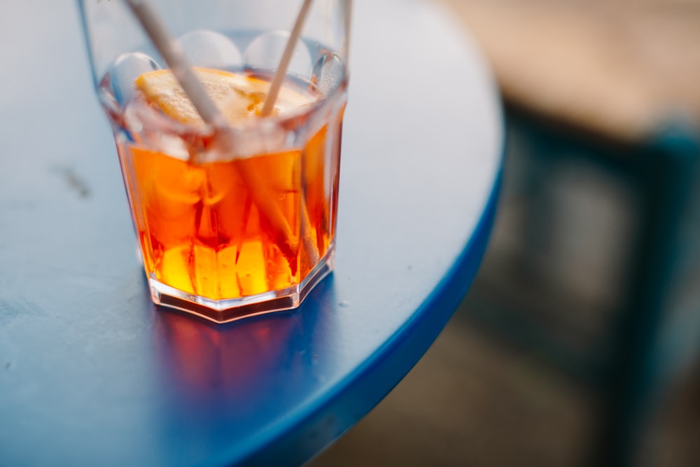 un vaso de té con hielo y limón sobre una mesa azul