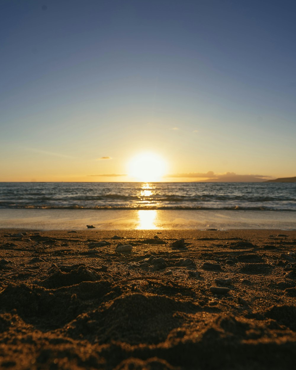 the sun is setting over the ocean on the beach