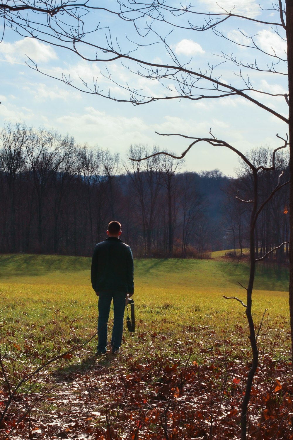 a man standing in a field next to a tree