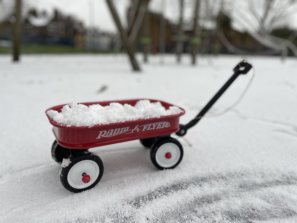 a red wagon filled with snow on top of a snow covered field