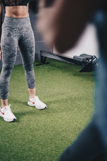 a woman standing on a green field wearing white sneakers