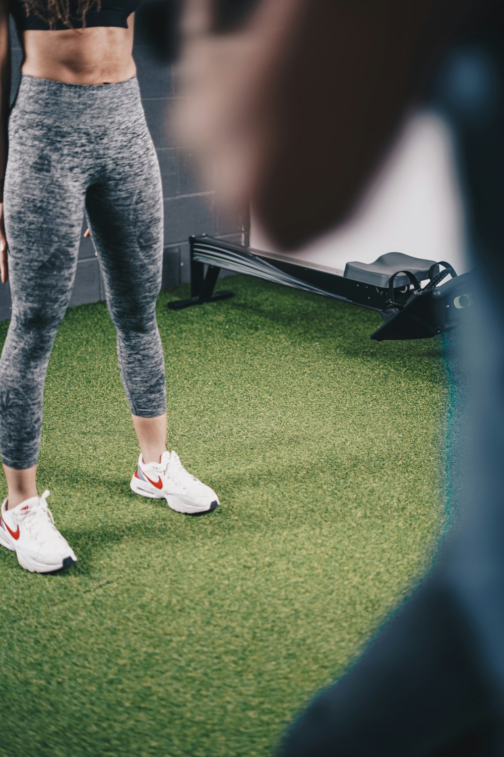 a woman standing on a green field wearing white sneakers