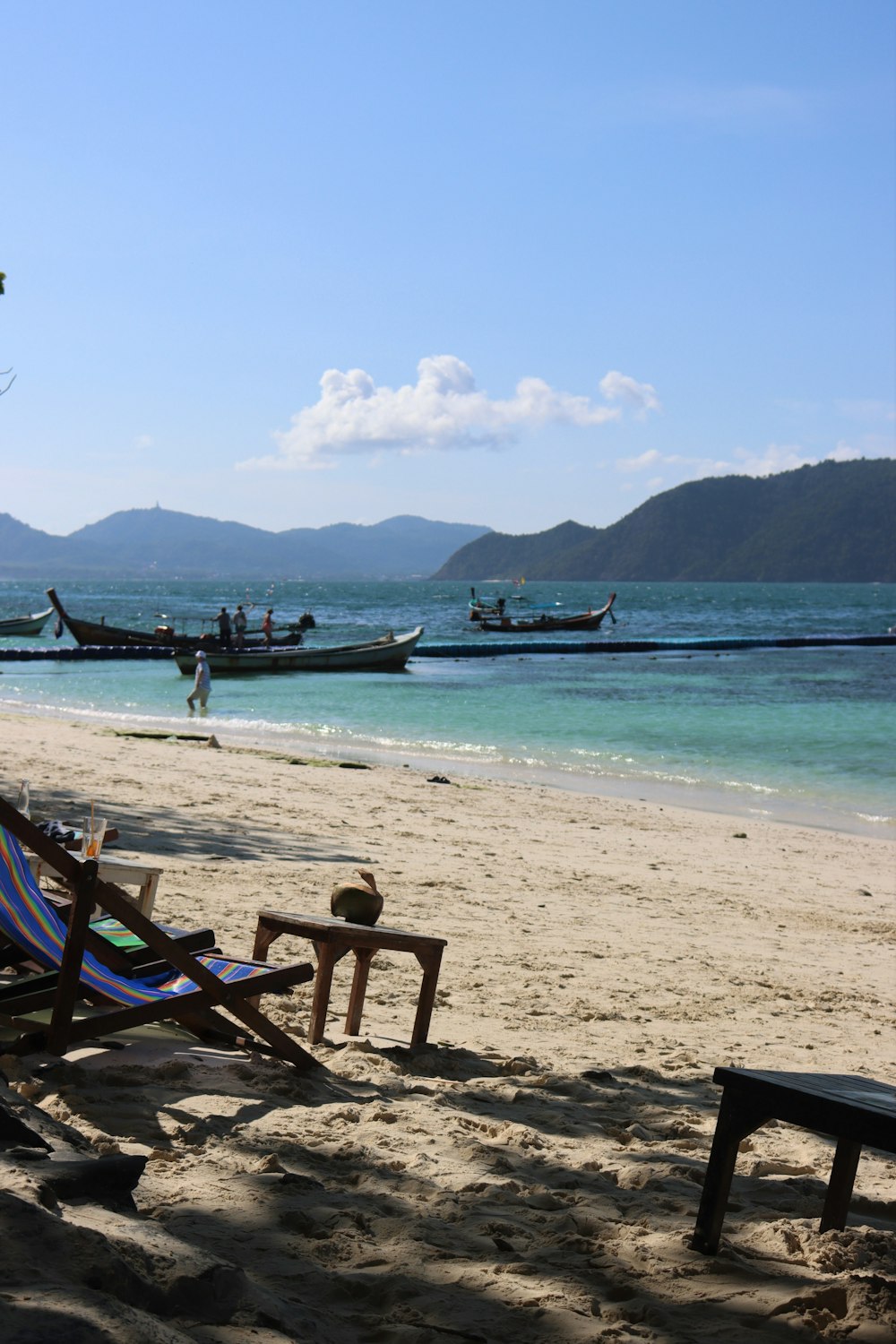 a beach with a few chairs and boats in the water